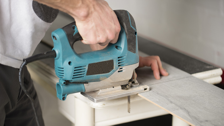 A person cutting a wooden plank with a saw