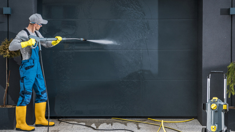 Man power washing black garage door