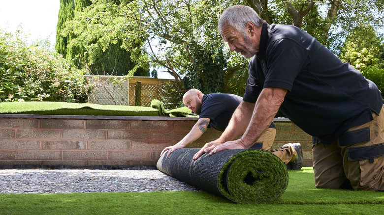 Men rolling out artificial grass