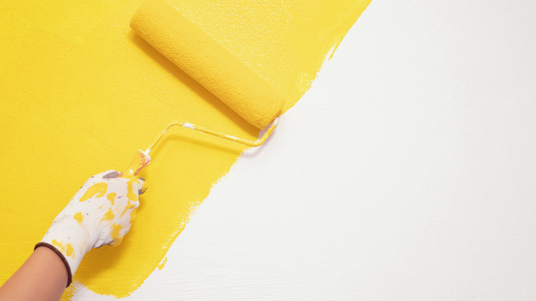 paint roller painting yellow wall