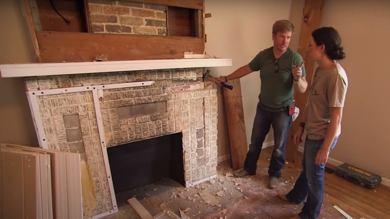 Chip and Joanna Gaines removing bricks from fireplace