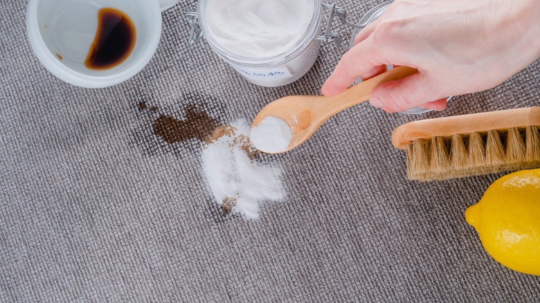 A person uses kitchen essentials to clean stains off of a carpet