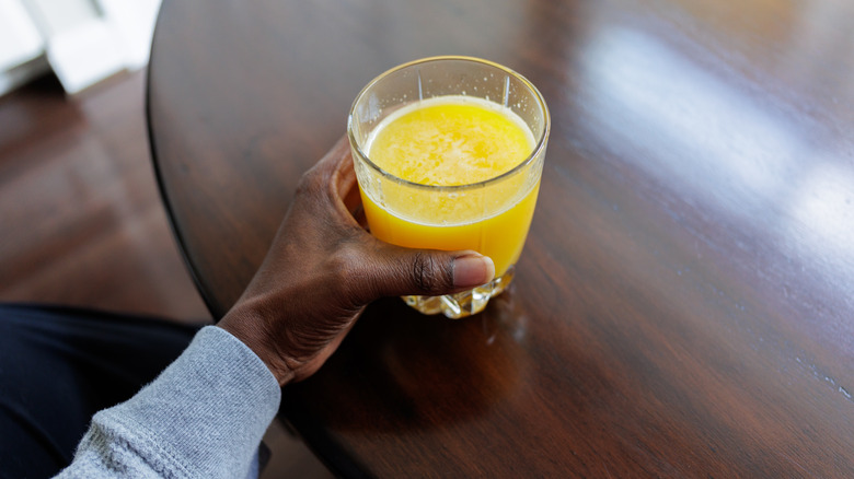 person holding glass of orange juice