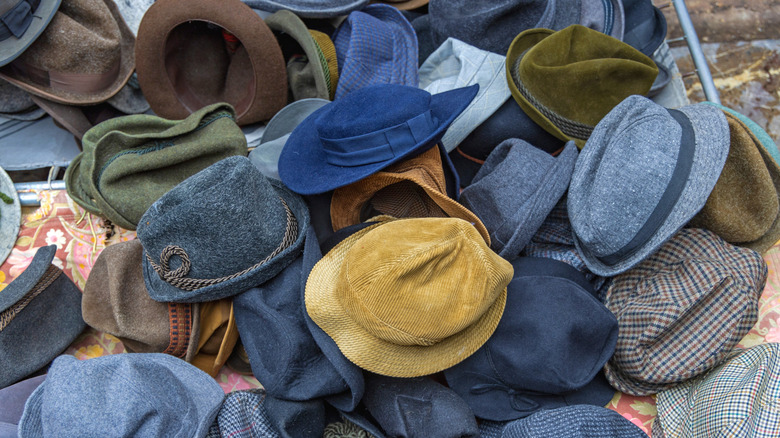 A messy pile of hats covers a table.