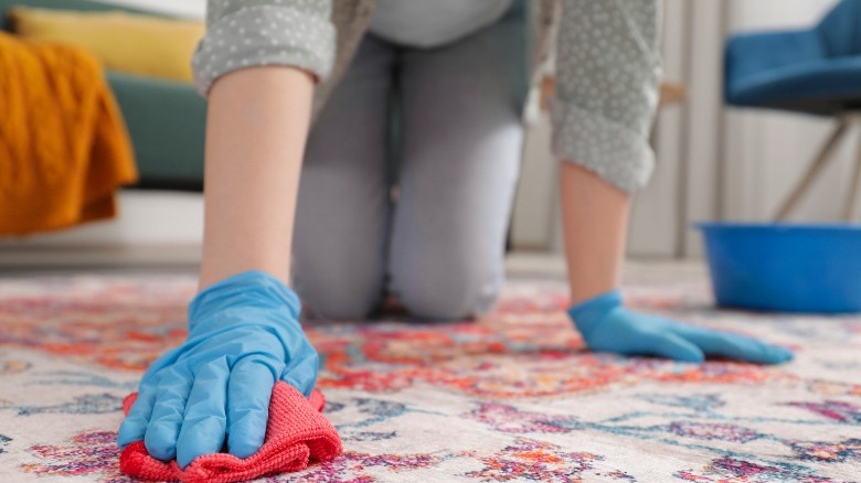 person wiping stain off carpet