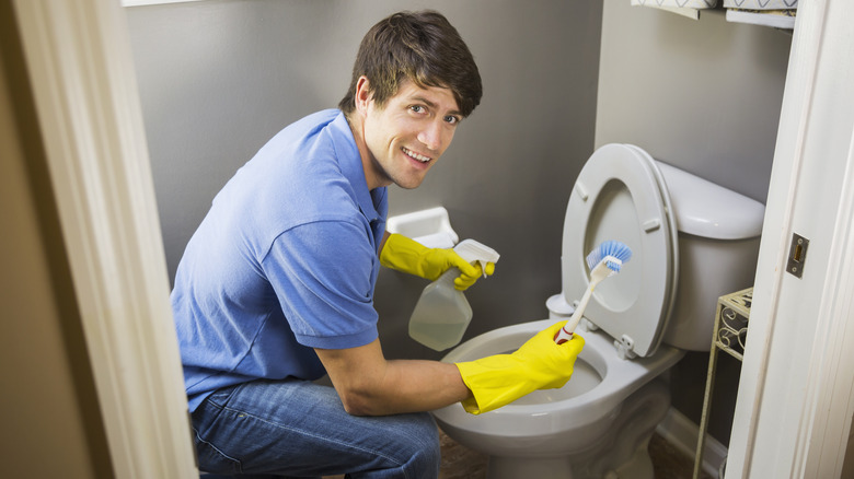 Man cleans toilet with brush