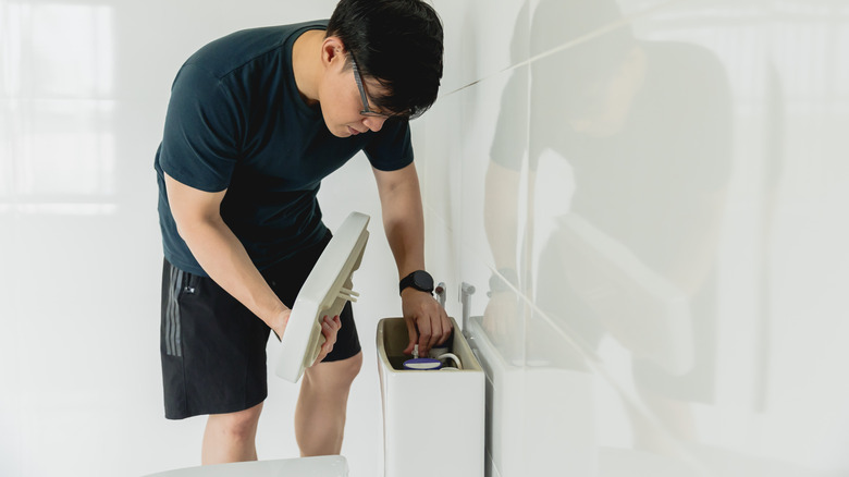 man adjusting toilet tank