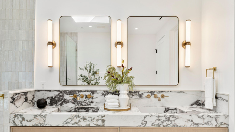 two sink vanity with sconce lighting over marble sinks