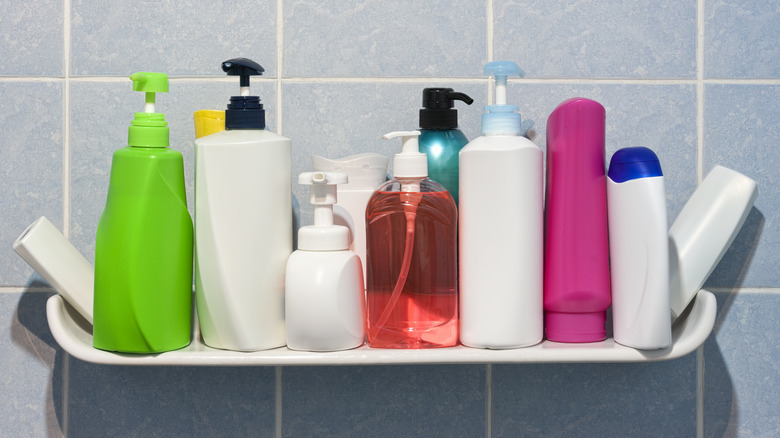 Many shampoo and soap bottles on a bathroom or shower shelf