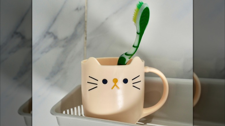 toothbrush in plastic cup with a cat's face on it