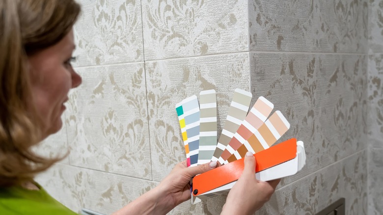 woman comparing paint swatch to tile