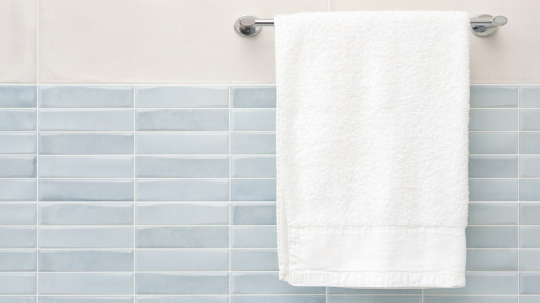 A white hand towel hanging in a bathroom