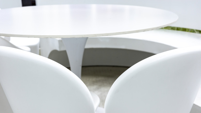 A white tulip table is in a white minimalist room