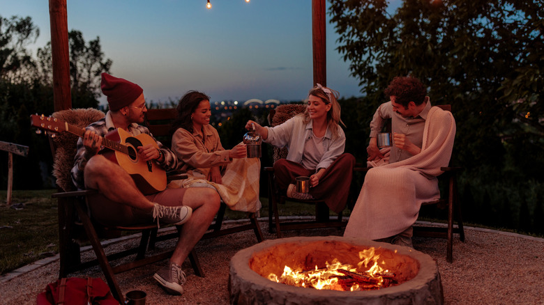 Happy people sitting around a fire pit