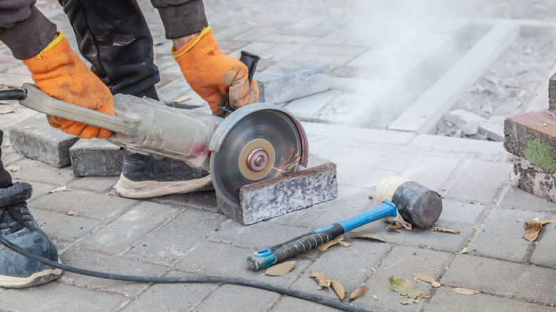 Person cutting paver brick with circular saw