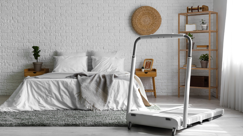 A large bedroom with white treadmill next to bed