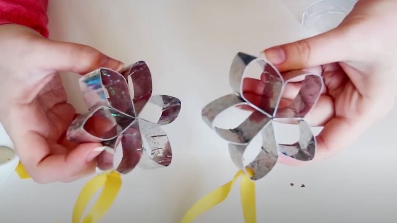 Person holding two silver origami flowers