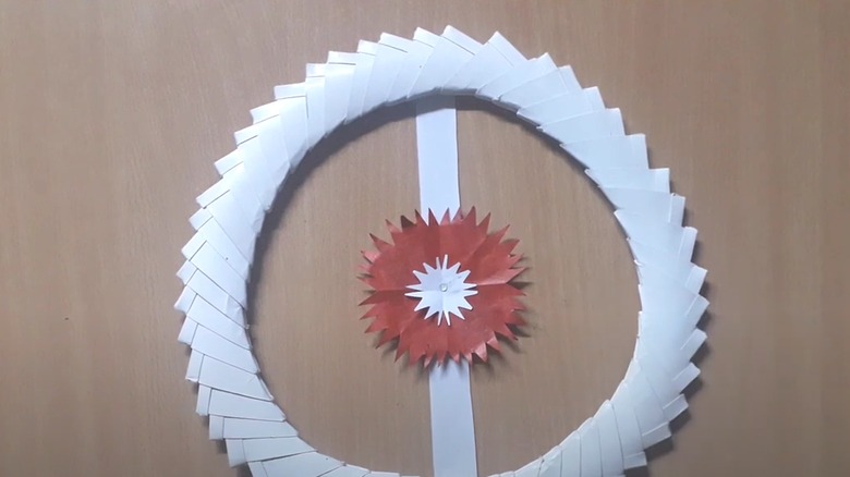 White wreath made from folded business cards with a paper flower in the middle