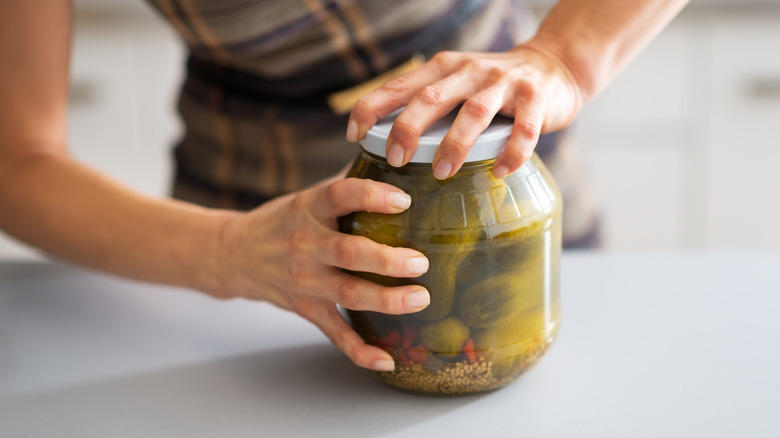 person opening a pickle jar