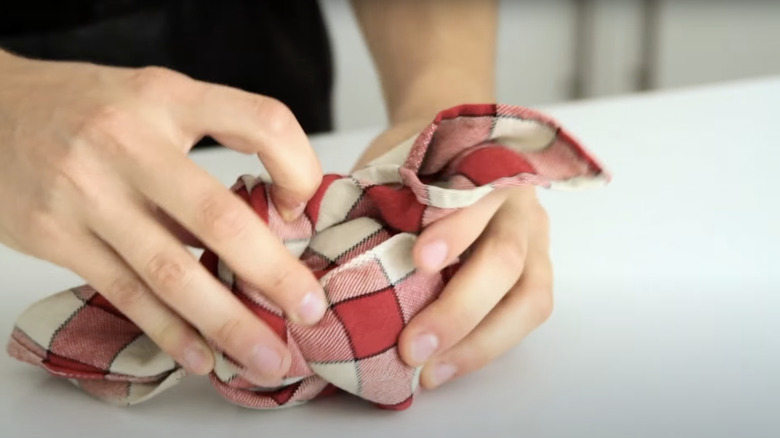 A person knotting a cloth napkin to create a reusable bag.