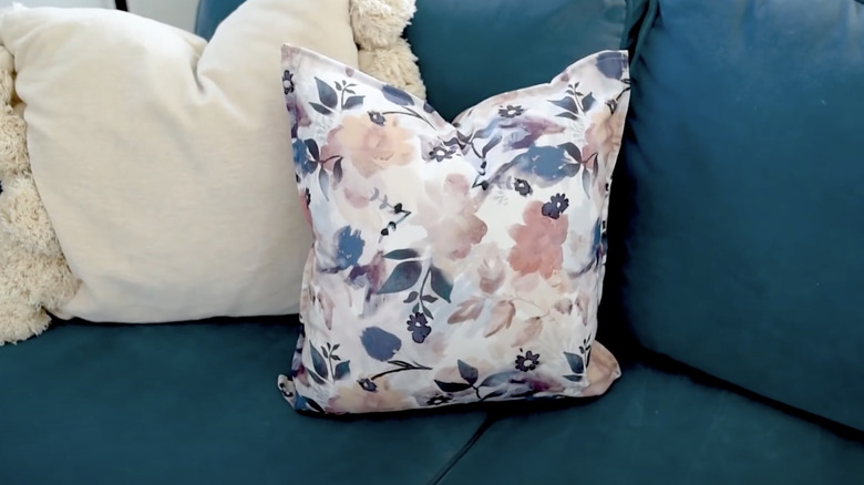 Cushion made from floral patterned cloth napkins perched on a couch.