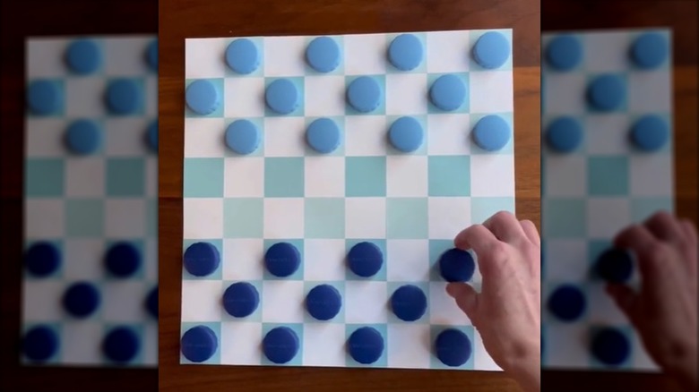 A homemade checkerboard with contact lens case tops used as checkers