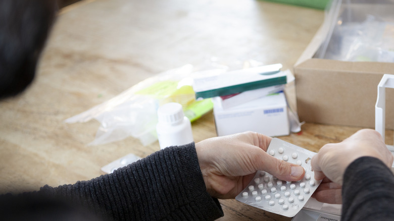 Person taking popping out pills to sort