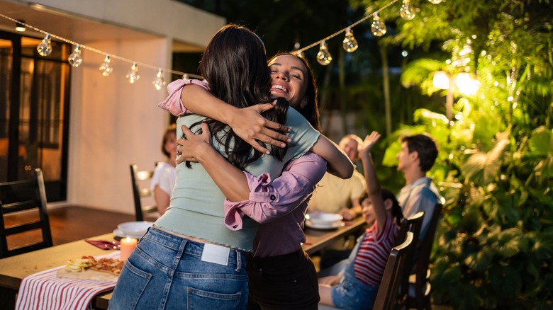women hugging near outdoor table