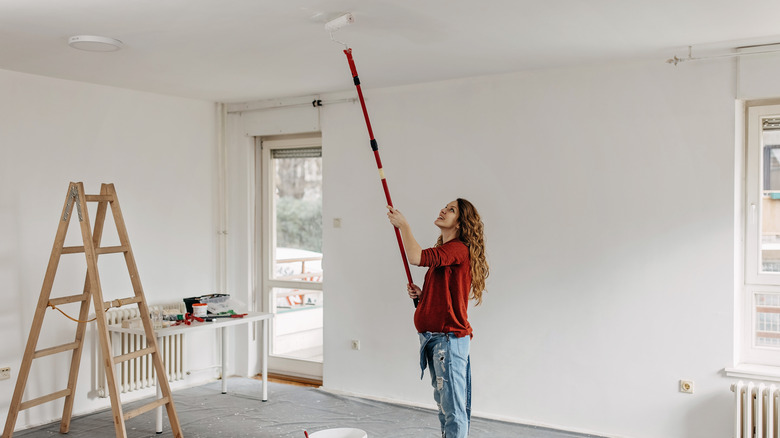 Woman painting ceiling with roller