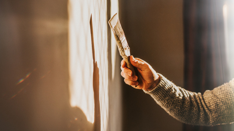 A person paints a dark wall