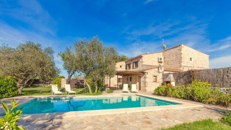 stone estate with pool and chairs 