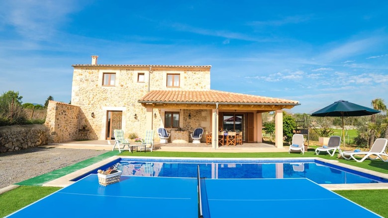 stone mansion with pool and ping pong table