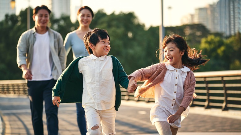 A boy and girl hold hands with their parents.