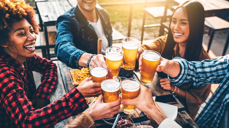 A group of friends cheers with glasses of beer.