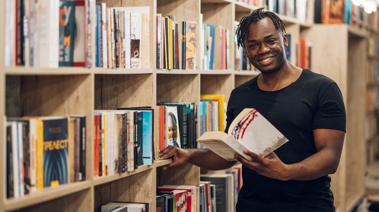 A man holding a book in a bookstore.