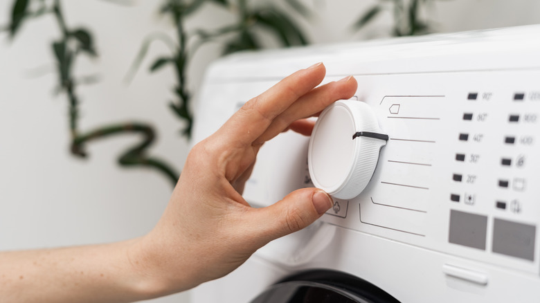 Person adjusting washing machine setting