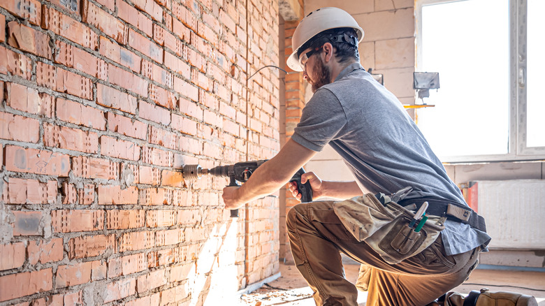 man drilling in brick wall