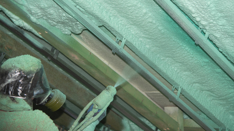 Worker in protective equipment using spray foam method to insulate an attic