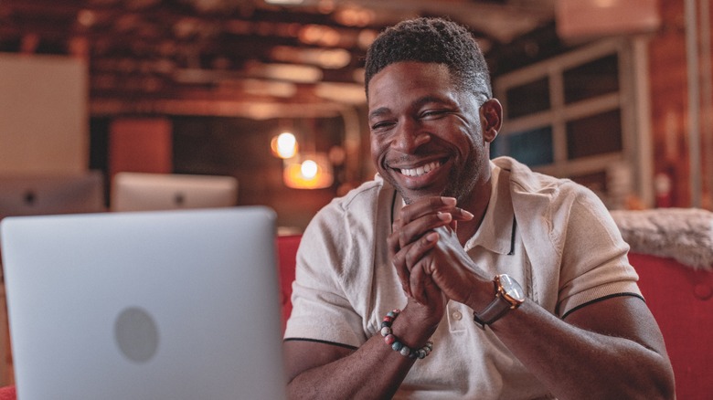 Andrew Tyree smiling and working on laptop