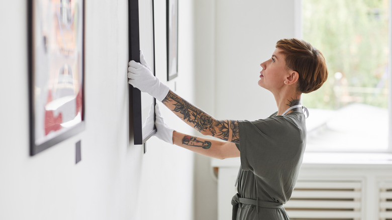 person hanging art on wall