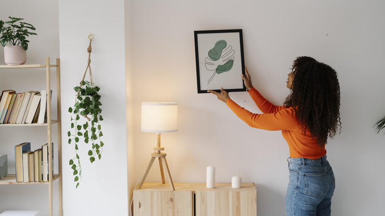 Woman taking down framed art from her wall