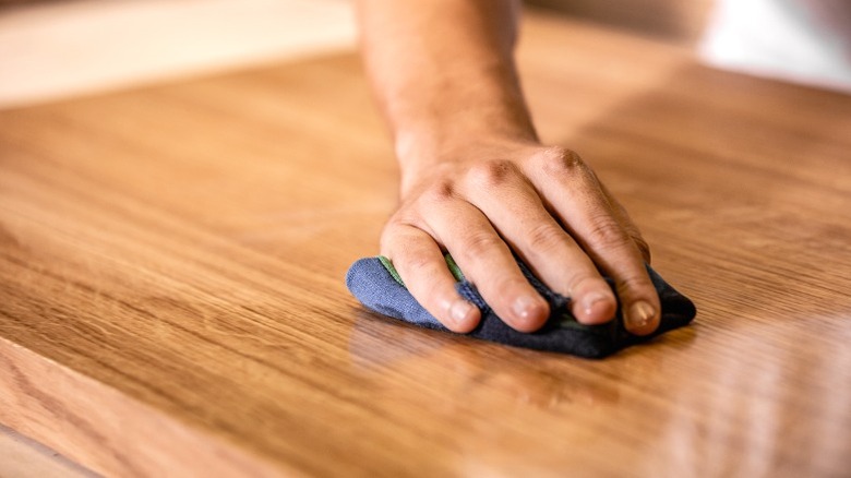 Closeup of hand wiping oil into wood table top