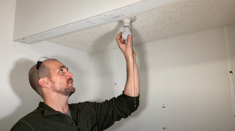 Man replacing a pull chain light fixture.