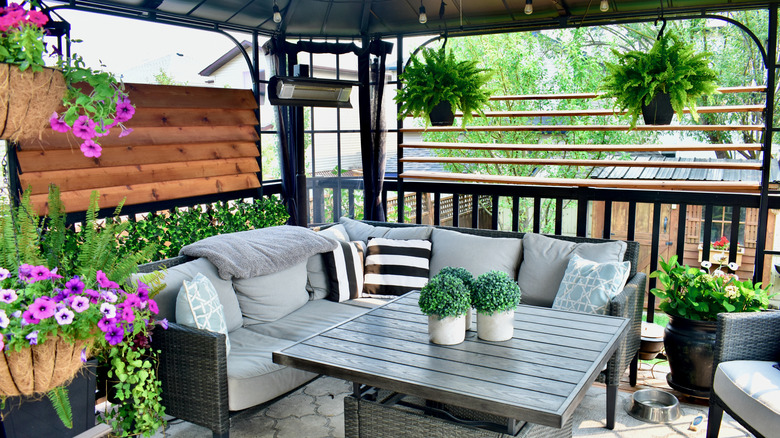 A porch has multiple colorful hanging baskets.