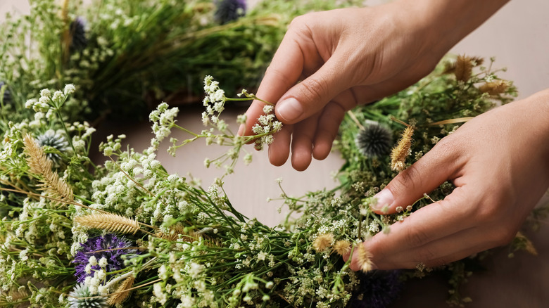 hands placing flowers on wreath