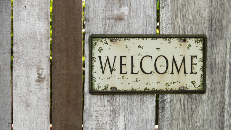 Wood fence with sign attached saying "Welcome"