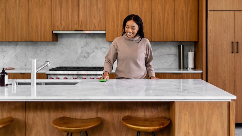 Woman polishing countertop in kitchen