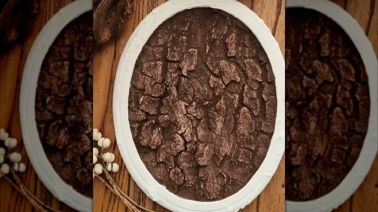 A painted plaster mold of tree bark rests on a wooden table