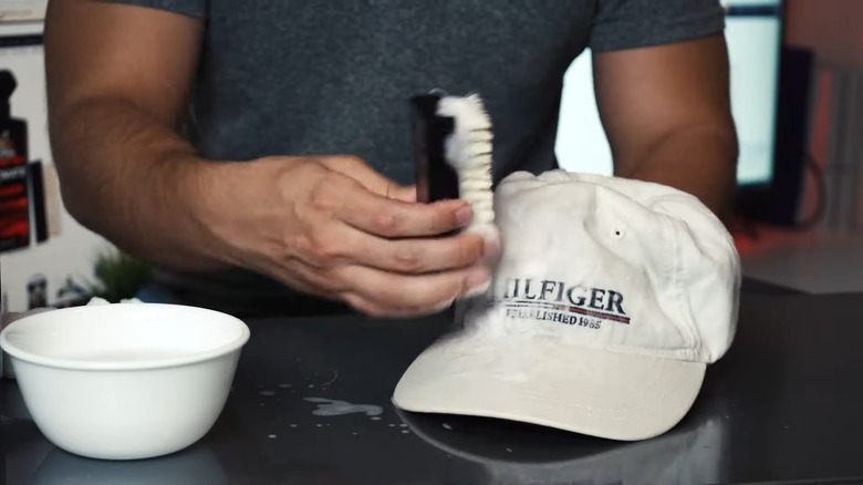 man scrubbing white cap