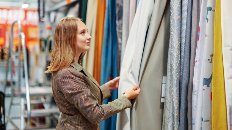 A woman looks at curtains on display